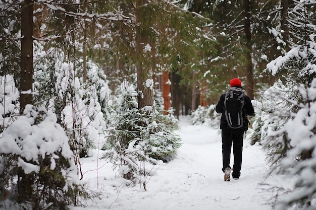 Un uomo viaggia con uno zaino. Escursione invernale nella foresta. Turista in una passeggiata in inverno nel parco.