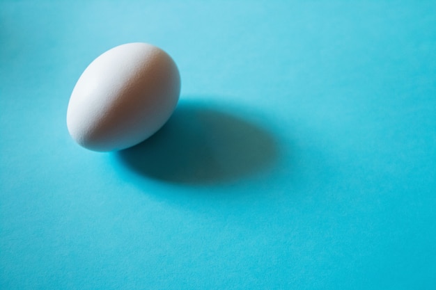 Un uovo bianco sul tavolo blu