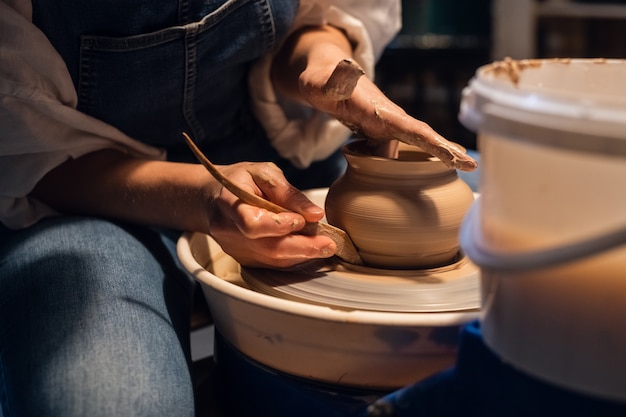 Un vasaio esperto una ragazza in uno studio d'arte fa una pentola di argilla con le sue mani.