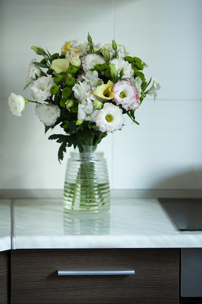 Un vaso di fiori si trova su un bancone con un piano di lavoro nero.