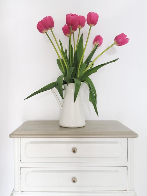 Un vaso di tulipani rosa si trova su un tavolo bianco