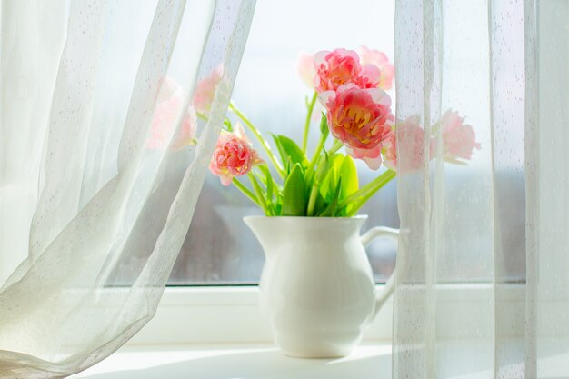 Un vaso di tulipani rosa sulla finestra