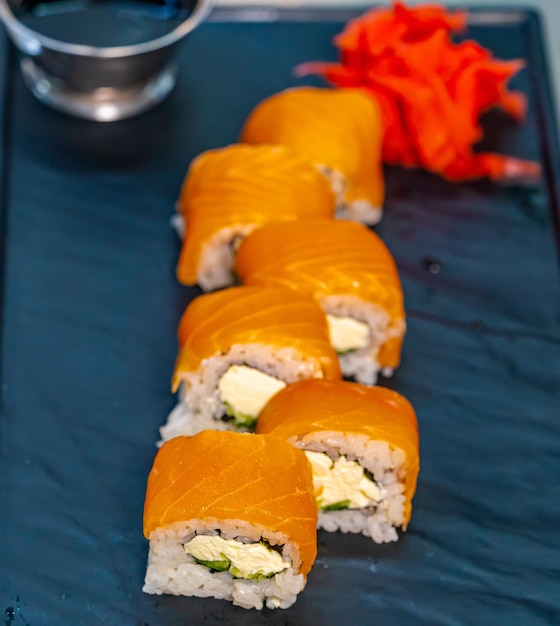 Un vassoio blu sormontato da sushi accanto a una scodella di salsa Delizioso piatto di sushi con contorno di salsa salata su un vivace vassoio blu