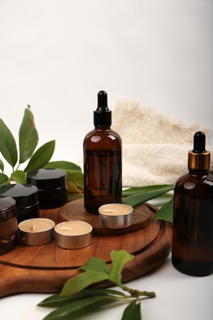 un vassoio di legno con bottiglie di cosmetici liquidi e una bottiglia di profumo su di esso con foglia verde