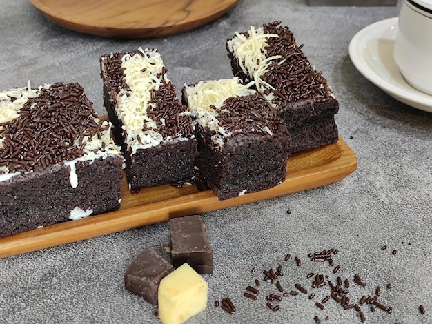 Un vassoio di legno di brownies al cioccolato con granelli sopra.