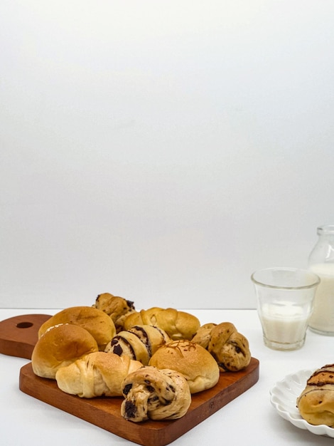 Un vassoio di prodotti da forno con sopra un bicchiere di latte e un piatto di pane.