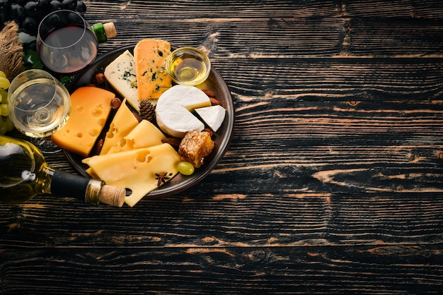 Un vasto assortimento di formaggi formaggio brie gorgonzola formaggio blu uva miele noci vino rosso e bianco su un tavolo di legno Vista dall'alto Spazio libero per il testo