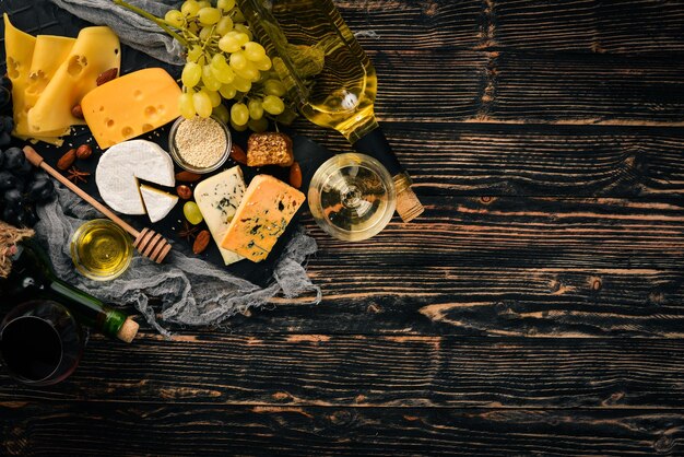 Un vasto assortimento di formaggi formaggio brie gorgonzola formaggio blu uva miele noci vino rosso e bianco su un tavolo di legno Vista dall'alto Spazio libero per il testo