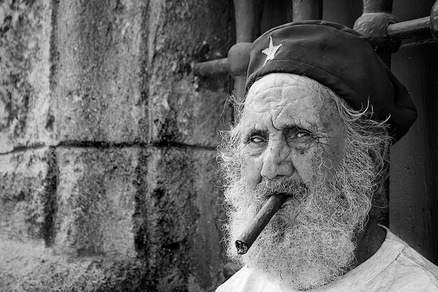 Un vecchio con la barba e il suo berretto fuma un sigaro in una strada della vecchia Havana.