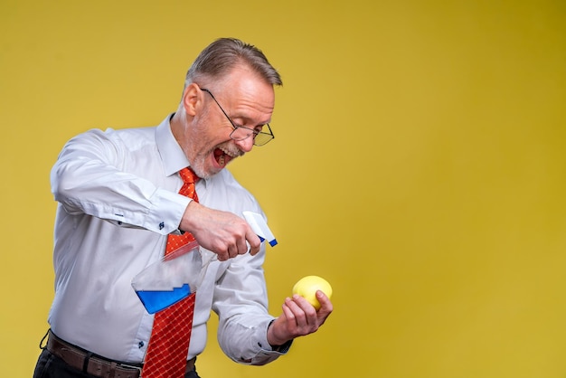 Un vecchio con la barba tiene una mela gialla L'uomo igienizza la frutta isolata su sfondo giallo