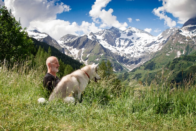 Un vecchio e un cane da slitta camminano. Pensionato attivo per il tempo libero. Cammina con Siberian Husky.