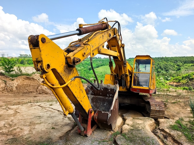 Un vecchio escavatore giallo è abbandonato in una vecchia cava.