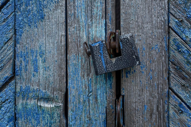 Un vecchio lucchetto su un cancello di legno spogliato blu Proteggi la proprietà e la privacy Primo piano