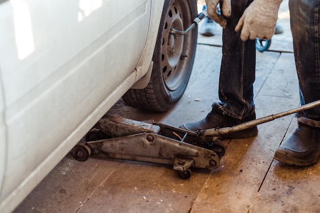 Un vecchio martinetto solleva una ruota in primo piano in un'officina per automobili