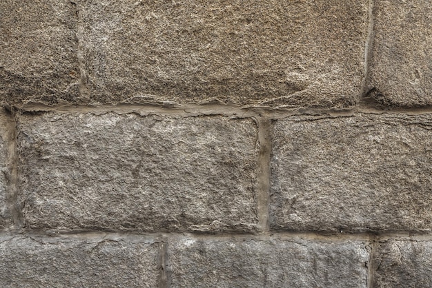 Un vecchio muro di blocchi di pietra con molti segni di usura evidenti sulla superficie
