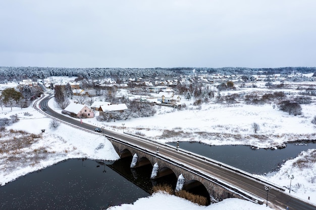 Un vecchio ponte di pietra con archi sul fiume Abava in una giornata invernale nevosa Kandava Lettonia