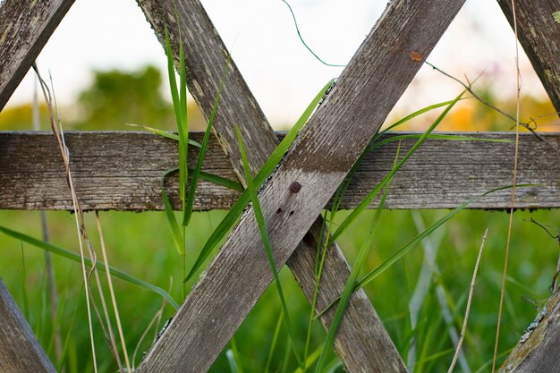 Un vecchio recinto di legno con un campo verde paese dietro di esso.