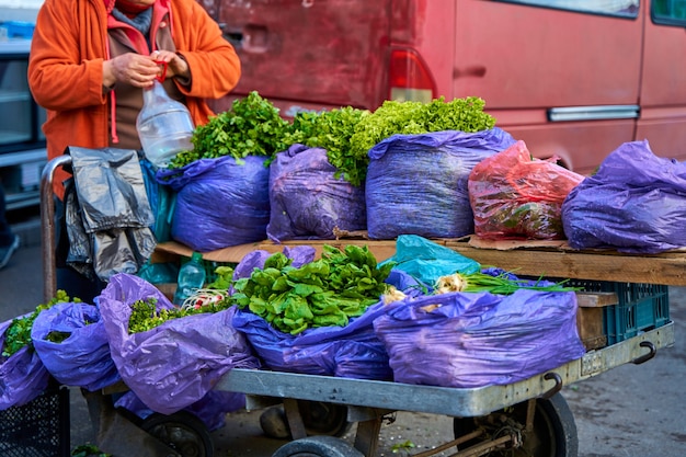 Un venditore ambulante vende lattuga fresca da un carretto per strada.