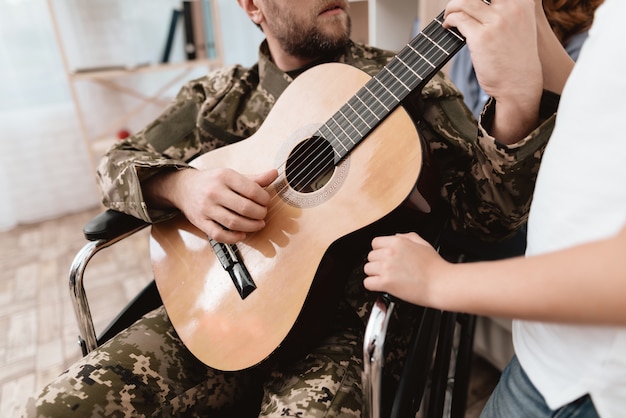 Un veterano su una sedia a rotelle suona la chitarra.