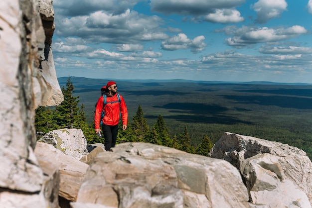 Un viaggiatore tra le Montagne Rocciose. Un uomo è un viaggiatore con uno zaino tra le rocce. Zaino in spalla in montagna. Turista estremo dello zaino in spalla nella natura selvaggia. Viaggi nazionali e trekking.