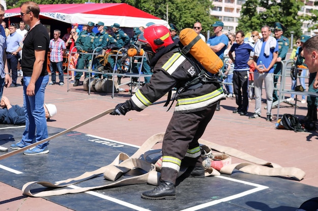 Un vigile del fuoco in una tuta ignifuga e un casco che corre con un pallone di ossigeno che tira la presa