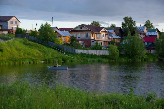 Un villaggio sulla sponda del fiume con erba verde brillante e un bel cielo