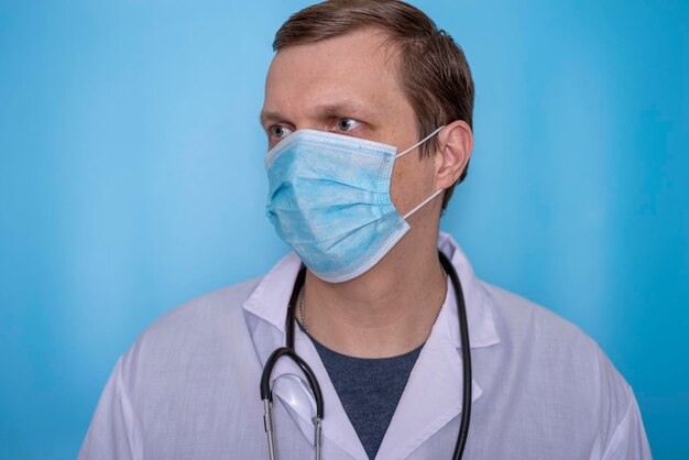 Un virologo maschio in maschera e vestaglia su sfondo blu