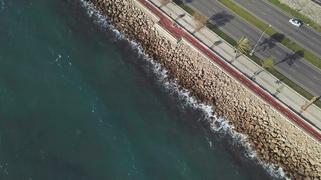 Un volo aereo che segue le macchine sull'autostrada lungo una costa rocciosa vista aerea di