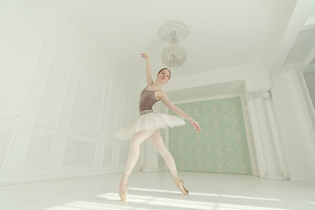una ballerina in un bodysuit leggero e tutu in piedi contro il muro che mostra elementi di ballet