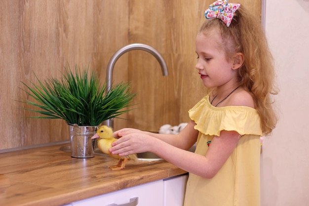 Una bambina a Pasqua con piccoli anatroccoli gialli Accanto alla torta e alle uova dipinte Holiday Family Happiness