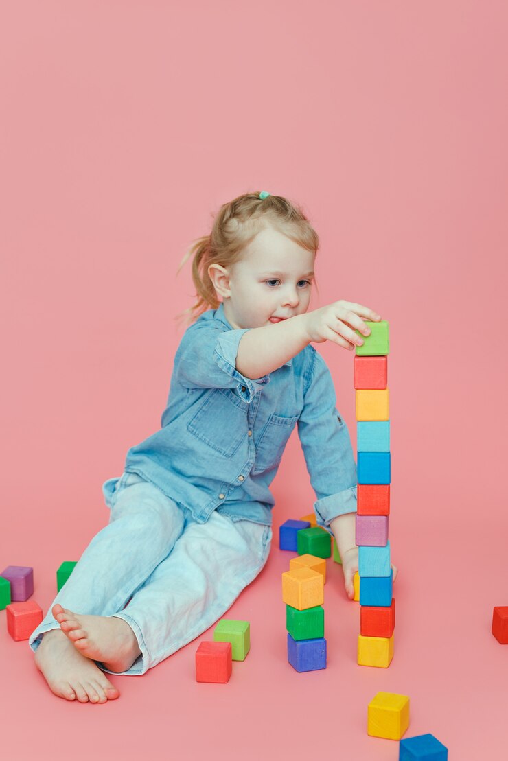 Una bambina affascinante costruisce una torre di cubi colorati di legno.