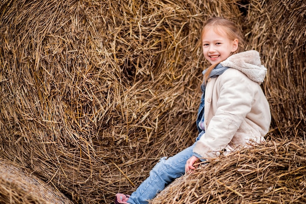 Una bambina allegra si siede su un pagliaio