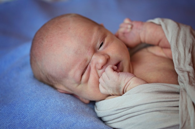 Una bambina appena nata si morde le dita e guarda con un occhio