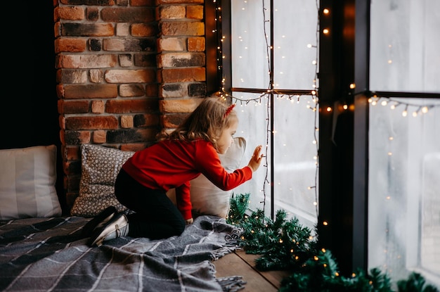 una bambina aspetta Babbo Natale alla finestra