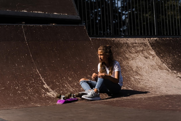 Una bambina attiva dopo la caduta da un penny board si è infortunata seduta e sente dolore sulla rampa sportiva nel parco giochi dello skate park