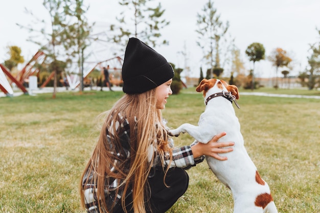 Una bambina bacia e abbraccia il suo cane Jack Russell terrier nel parco L'amore tra il proprietario e il cane un bambino tiene in braccio un cane