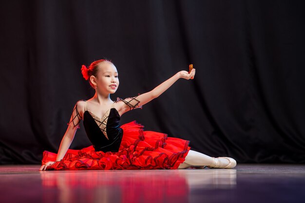 Una bambina ballerina sta ballando sul palco in tutù su scarpe da punta con castanedas, la classica variazione di Kitri.