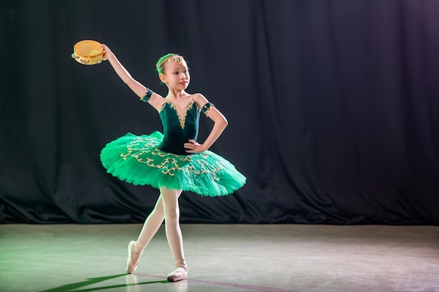 Una bambina ballerina sta ballando sul palco in tutù su scarpe da punta con un tamburello, una variazione classica di Esmeralda.