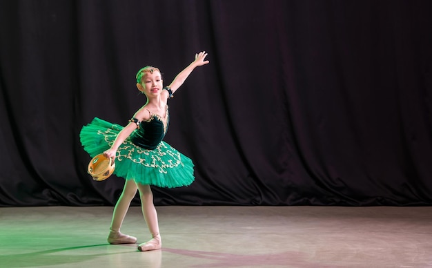 Una bambina ballerina sta ballando sul palco in tutù su scarpe da punta con un tamburello, una variazione classica di Esmeralda.