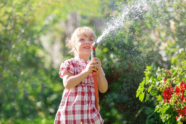 una bambina bionda cammina in una giornata di sole si prende cura del giardino