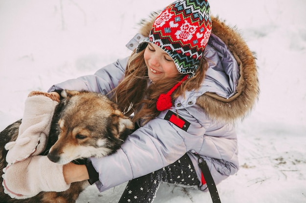 Una bambina cammina con il suo cane nella foresta invernale.