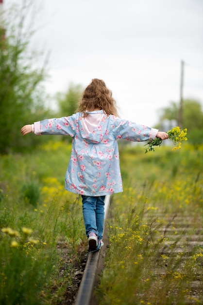 Una bambina cammina lungo i binari erbosi della ferrovia Ecologia Il concetto