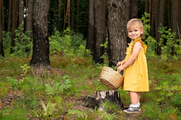 Una bambina cammina nel bosco con un cesto in mano