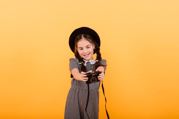 Una bambina carina che fa foto su sfondo giallo.