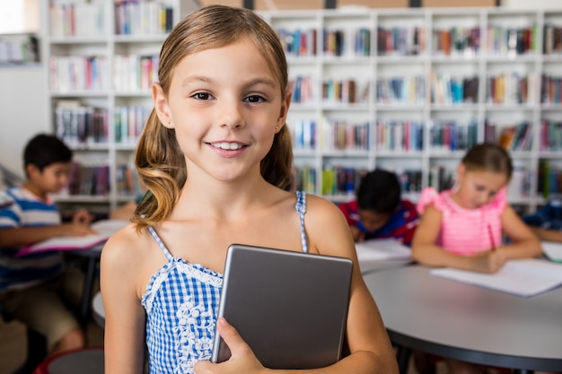 Una bambina carina che sorride alla macchina fotografica con tablet pc