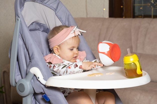 Una bambina carina di un anno versa i biscotti da un piatto