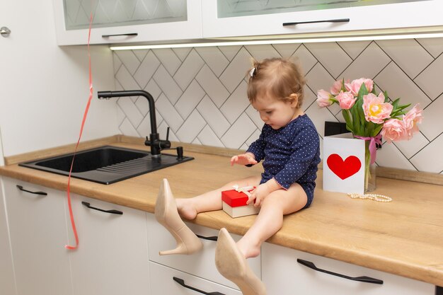 Una bambina carina è seduta in cucina con un mazzo di tulipani rosa bella cartolina regalo