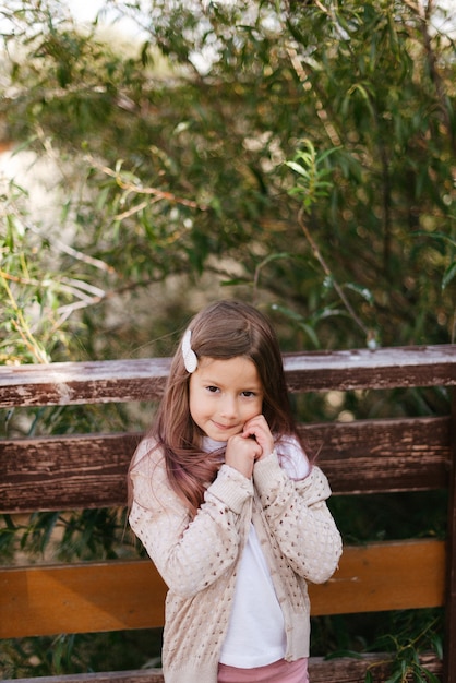 Una bambina carina in un maglione caldo sta con le braccia conserte