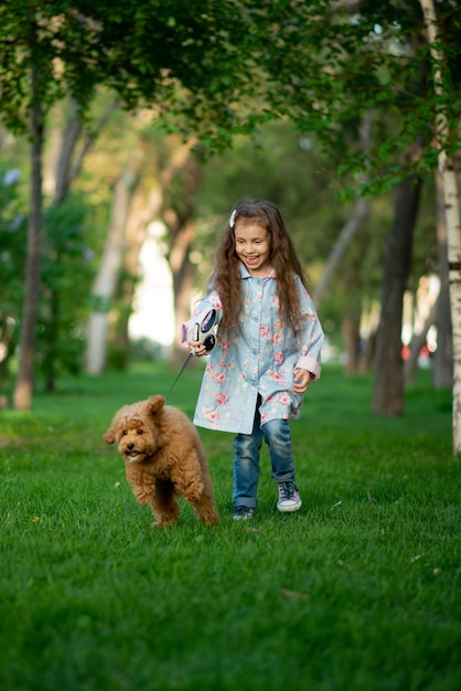 Una bambina carina in una passeggiata con il cane barboncino giocattolo