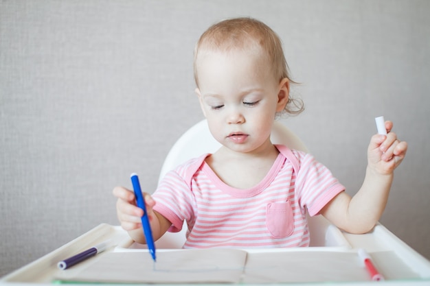 Una bambina cerca di disegnare con pennarelli